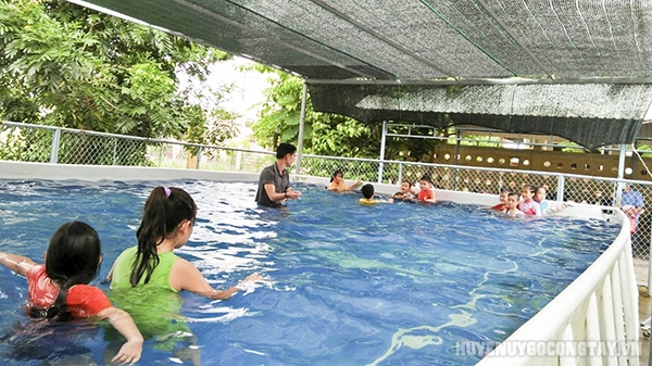 Giáo viên hướng dẫn bơi cho các em học sinh