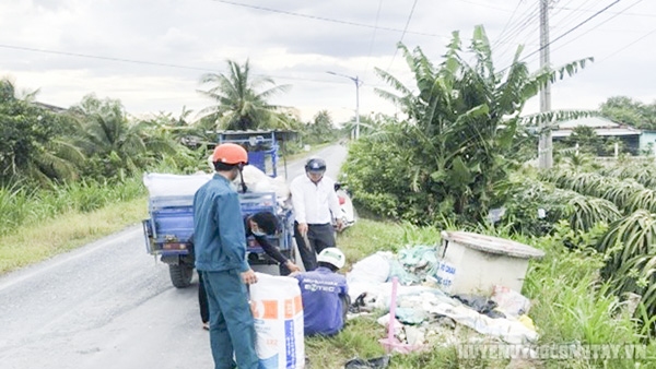 Cán bộ xã cùng người dân thực hiện thu gom rác tại các điểm ven đường